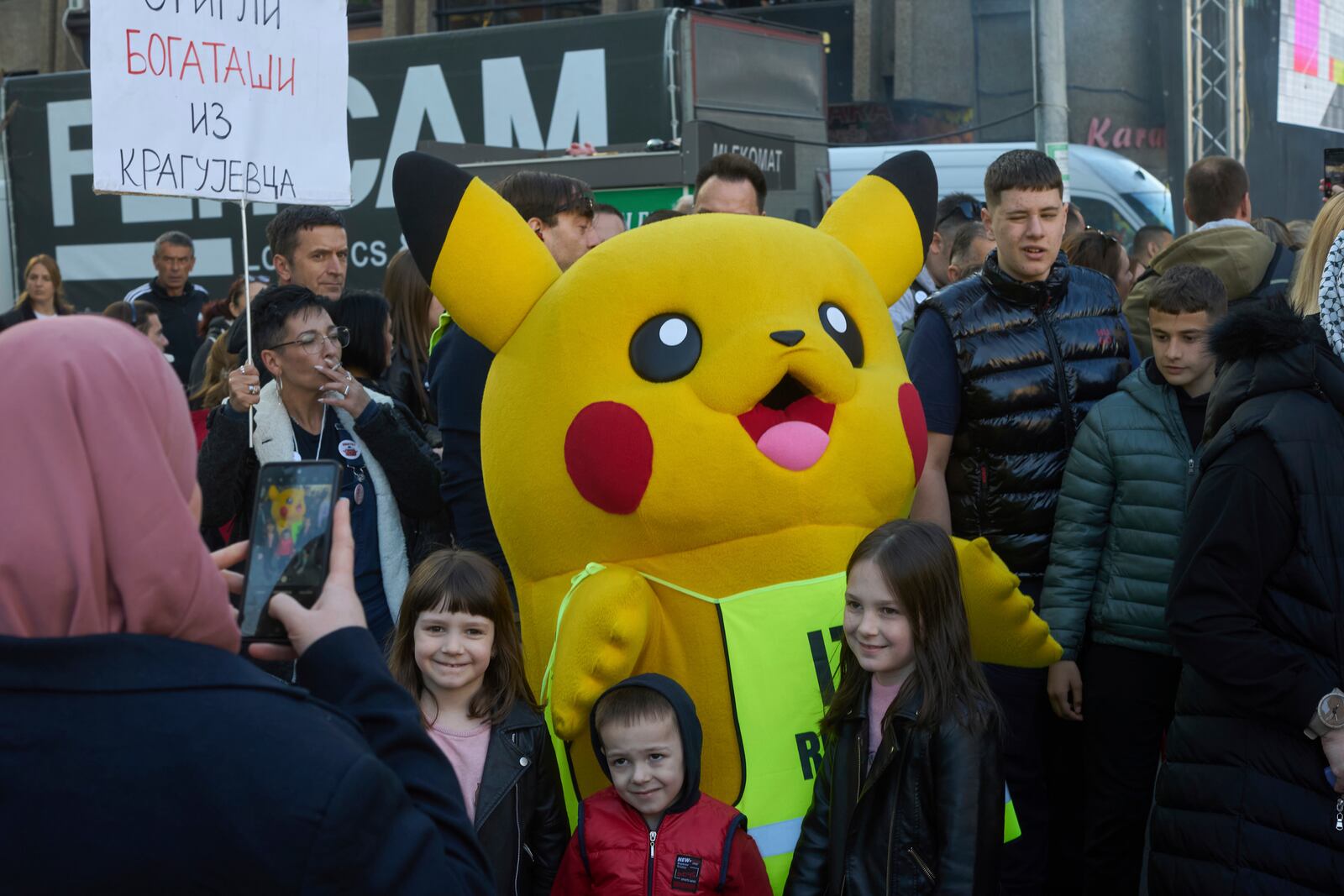 A person dressed in a Pikachu costume poses for photographs with people during an anti-corruption protest led by university students in the southwestern town of Novi Pazar, Serbia, Saturday, April 12, 2025. (AP Photo/Marko Drobnjakovic)