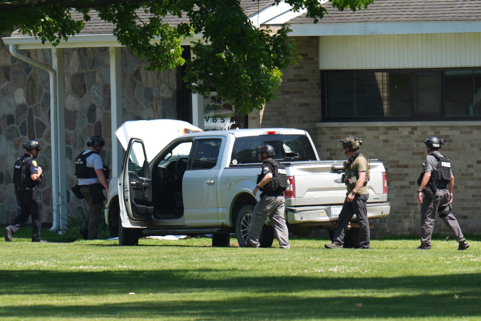Police walk by an idle vehicle near CrossPointe Community Church in Wayne, Mich., Sunday, June 23, 2025. (AP Photo/Paul Sancya)