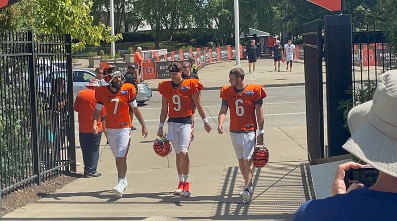 Joe Burrow (center) walks to practice Wednesday with fellow quarterbacks Jake Browning (right) and Will Grier. Laurel Pfahler/CONTRIBUTED