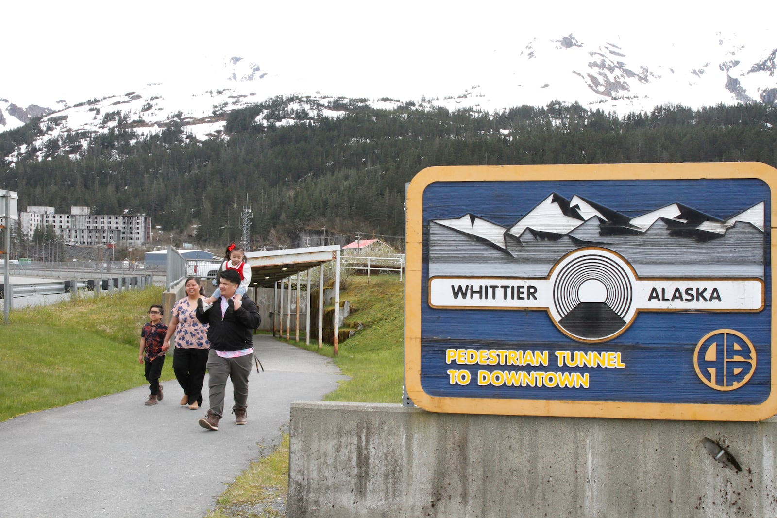 Michael Pese, with daughter Cataleya on his shoulders, and his wife, Tupe Smith, with their son Maximus exit a pedestrian tunnel underneath Whittier, Alaska, May 13, 2025. (AP Photo/Mark Thiessen)