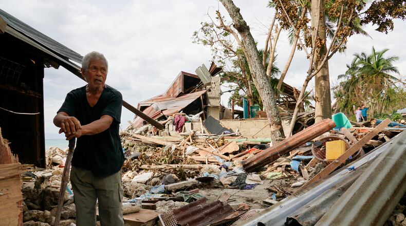 FILE -Bernardino Aspacio walks past rubbles from his damaged house due to Typhoon Rai in Alegria, Cebu province, central Philippines, Dec. 22, 2021. (AP Photo/Jay Labra, File)