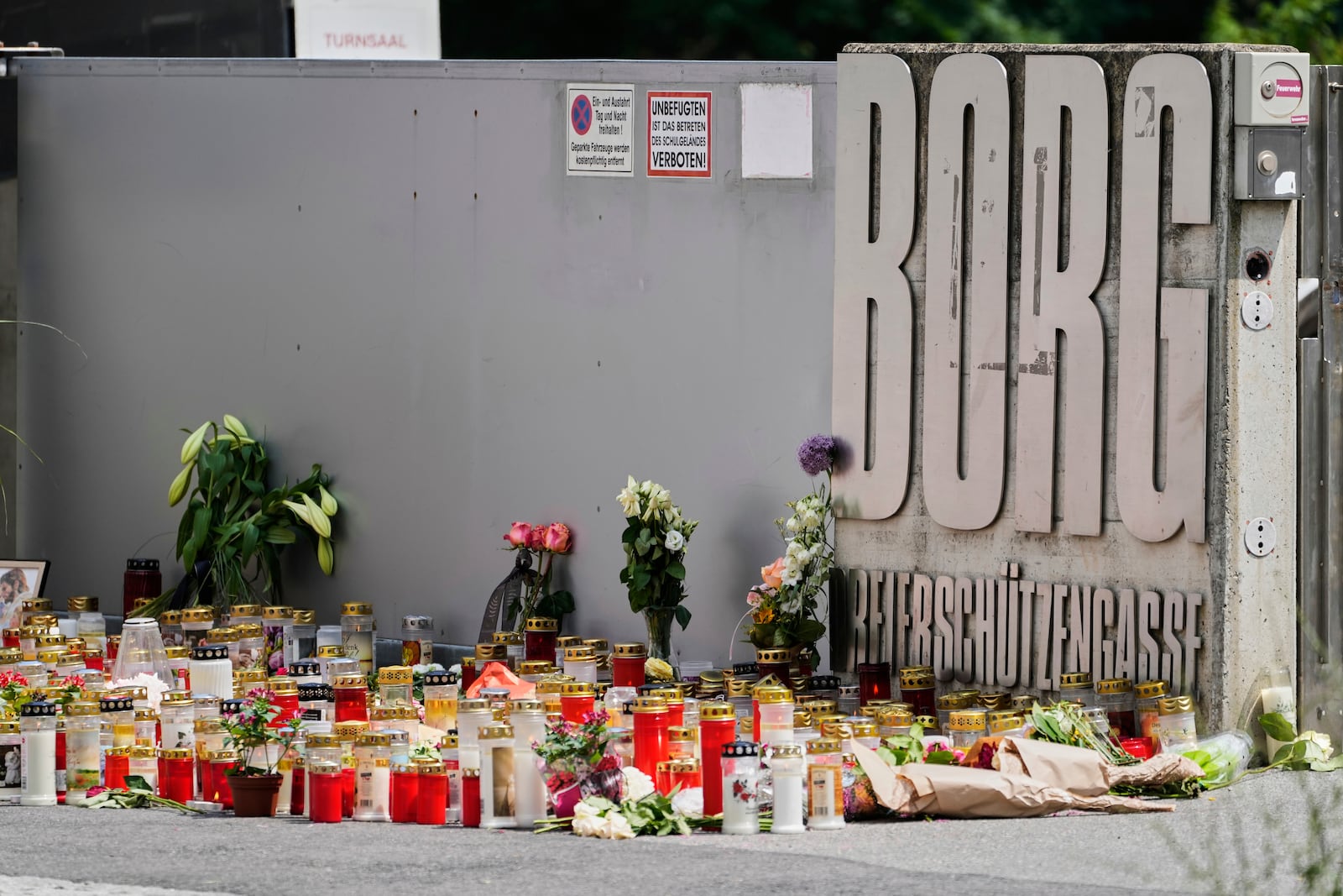 Flowers and candles are laid outside a school where a former student opened fire the day before fatally wounding several people and injuring many others before taking his own life, Graz, Austria, Wednesday, June 11, 2025. (AP Photo/Darko Bandic)