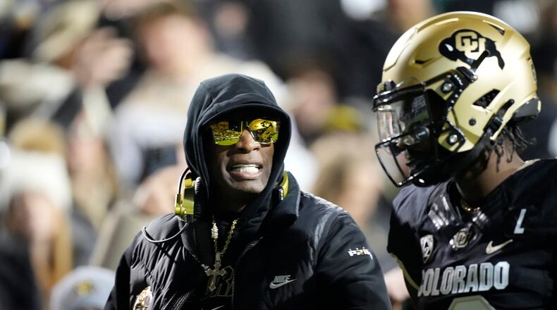 FILE - Colorado head coach Deion Sanders, left, talks to his son, quarterback Shedeur Sanders, in the first half of an NCAA college football game against Stanford Friday, Oct. 13, 2023, in Boulder, Colo. Deion Sanders is accomplishing what he pledged to do by overhauling his offensive line to better protect his often-hit quarterback son. The Colorado coach reached into the transfer portal and brought in linemen from the University of Houston, Connecticut, Indiana and UTEP. (AP Photo/David Zalubowski, File)