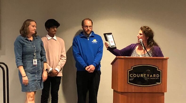Project Woman executive director Laura Baxter, right, and colleague Audrey Ferryman, left, present the organization's Purple Ribbon Award for service and volunteerism to the organization to Ridgewood School student council president Mahed Rizvi and teacher and student council advisor Dan Metzger during a ceremony on Wednesday afternoon.