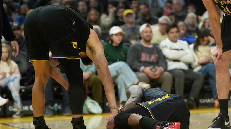 Golden State Warriors guard Stephen Curry, left, checks on forward Jimmy Butler III during the second half of an NBA basketball game against the Miami Heat in San Francisco, Monday, Jan. 19, 2026. (AP Photo/Jeff Chiu)