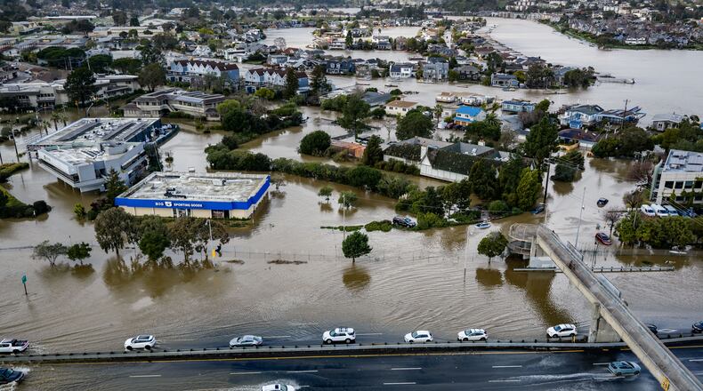 Cars drive on highway 101 flooded by the "King Tides", occurring when the sun, moon and Earth align, causing a stronger gravitational pull Saturday, Jan. 3, 2026, near Corte Madera in Marin County, Calif. (AP Photo/Ethan Swope)