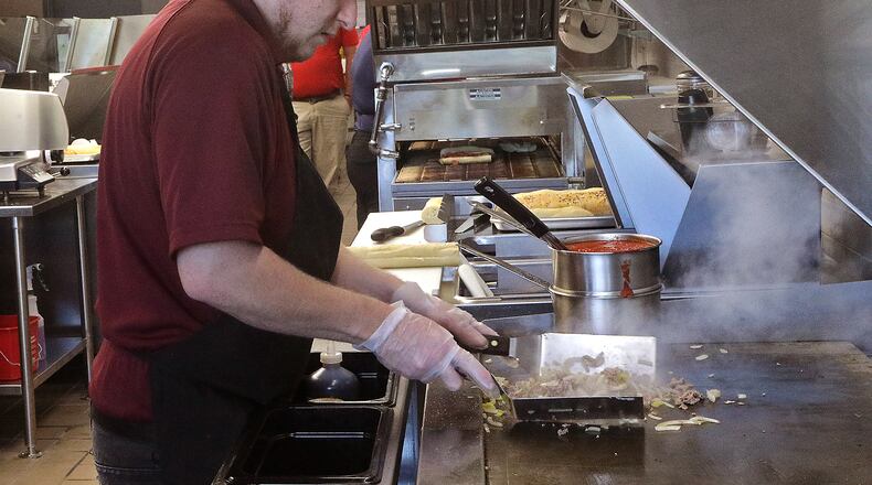 Steam rolls off steak, onions and peppers sizzling on the grill as Josh Zwisler makes a cheese steak sandwich for a customer Thursday, Sept. 29, 2022, at the new Penn Station East Coast Subs on East National Road. The new sub shop, located near the intersection with Tuttle Road, opened Wednesday. It is the second Penn Station in Springfield, joining one on Bechtle Avenue. BILL LACKEY/STAFF