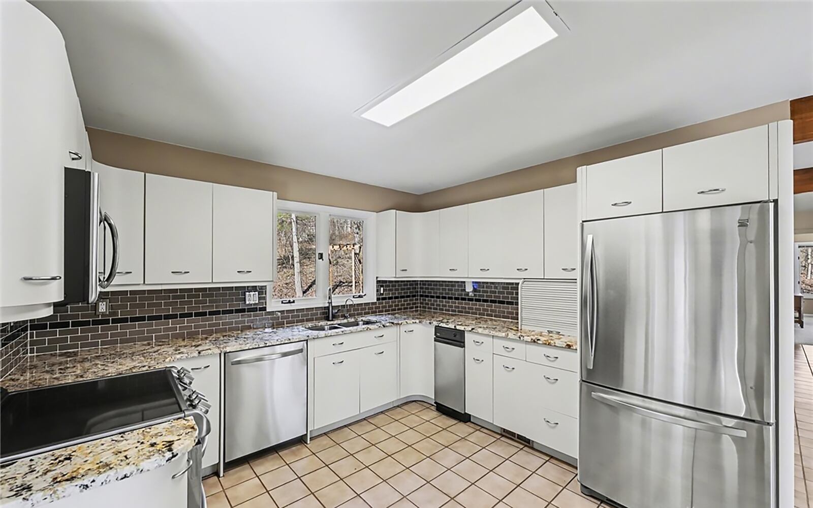 The kitchen has tile flooring, stainless appliances, white cabinets with granite countertops and a tile backsplash. CONTRIBUTED