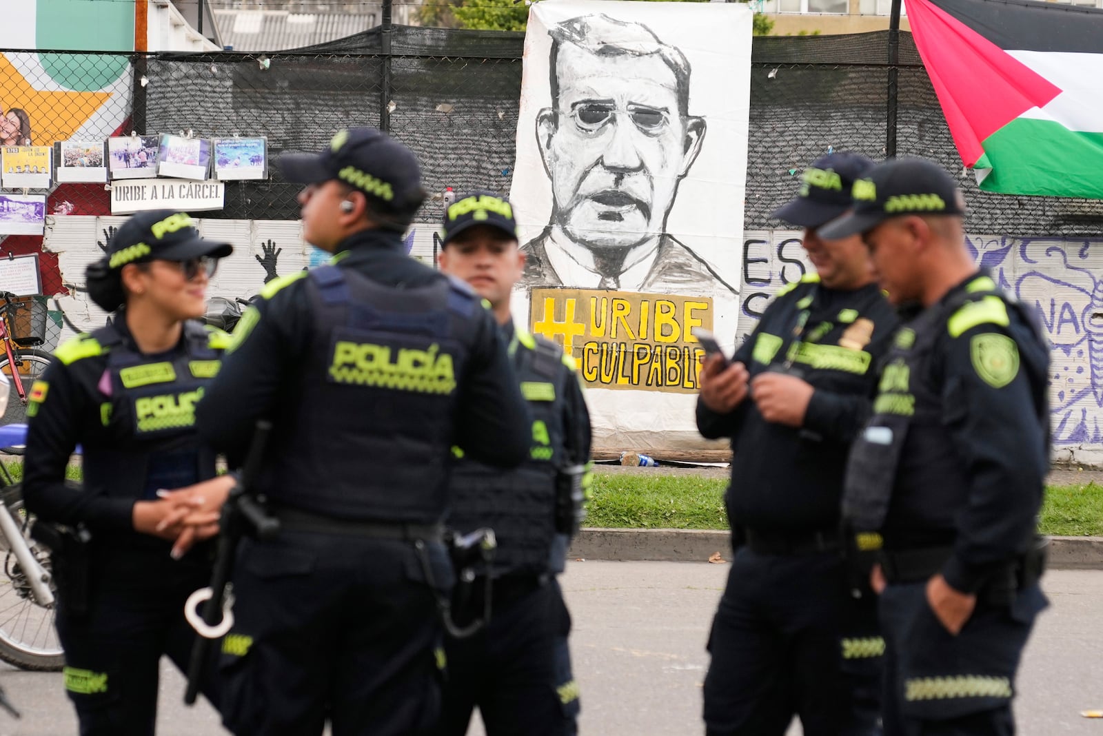 Police stand in front of a banner reading in Spanish "Uribe guilty" displayed by opponents of former President Alvaro Uribe outside the court where a verdict is expected in his trial for witness tampering, in Bogota, Colombia, Monday, July 28, 2025. (AP Photo/Fernando Vergara)