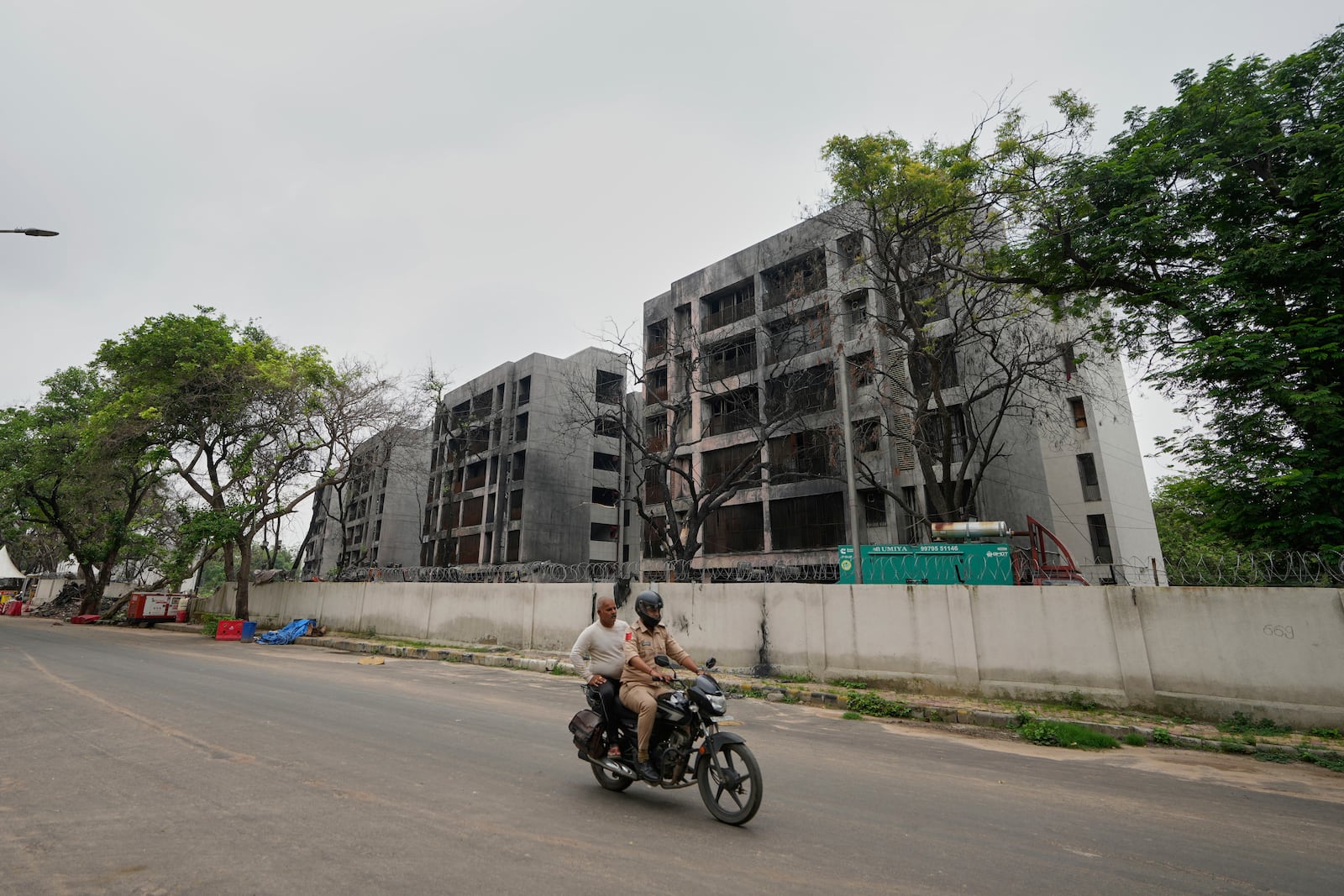 Policemen ride past buildings damaged in the June 12 Air India plane crash in Ahmedabad, India, Saturday, July 12, 2025. (AP Photo/Ajit Solanki)