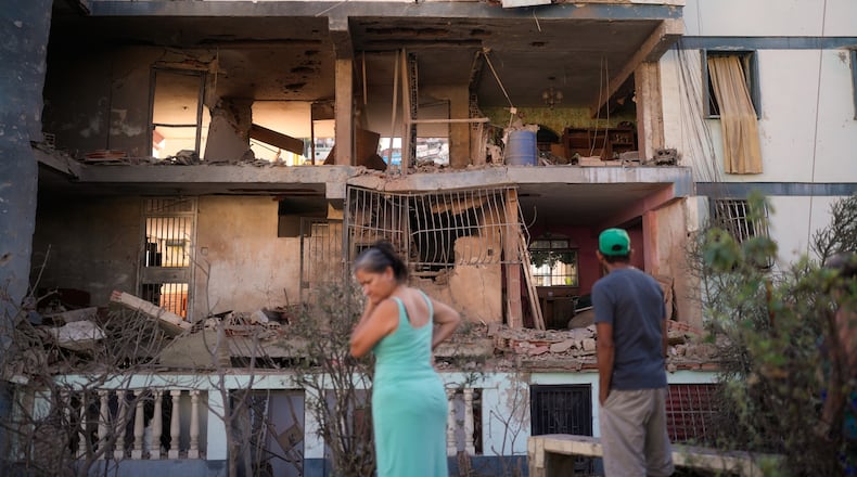 Residents look at a damaged apartment complex that neighbors say was hit during U.S. strikes to capture Venezuelan President Nicolás Maduro, in Catia La Mar, Venezuela, Sunday, Jan. 4, 2026. (AP Photo/Matias Delacroix)