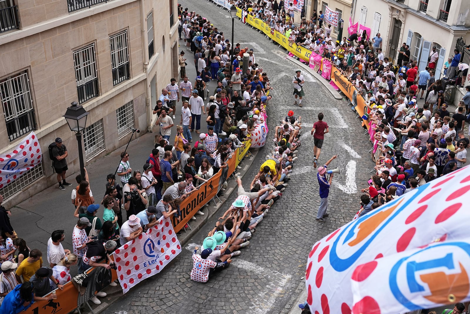 Cycling fans have fun on the street in the Montmartre district before the last stage of the Tour de France cycling race between Mantes-la-Ville and Paris, Sunday, July 27, 2025 in Paris (AP Photo/Laurent Cipriani)
