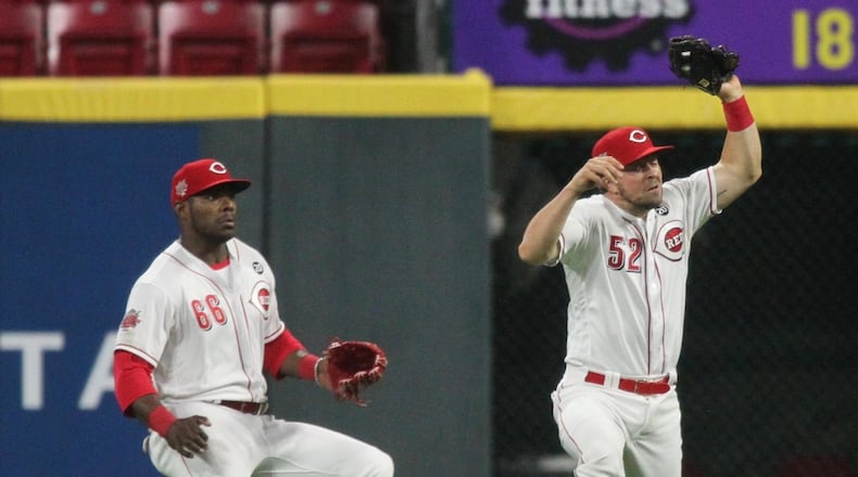 Reds second baseman Kyle Farmer, right, makes a catch in front of right fielder Yasiel Puig in the ninth inning against the Braves just after midnight on Friday, April 26, 2019, at Great American Ball Park in Cincinnati. David Jablonski/Staff