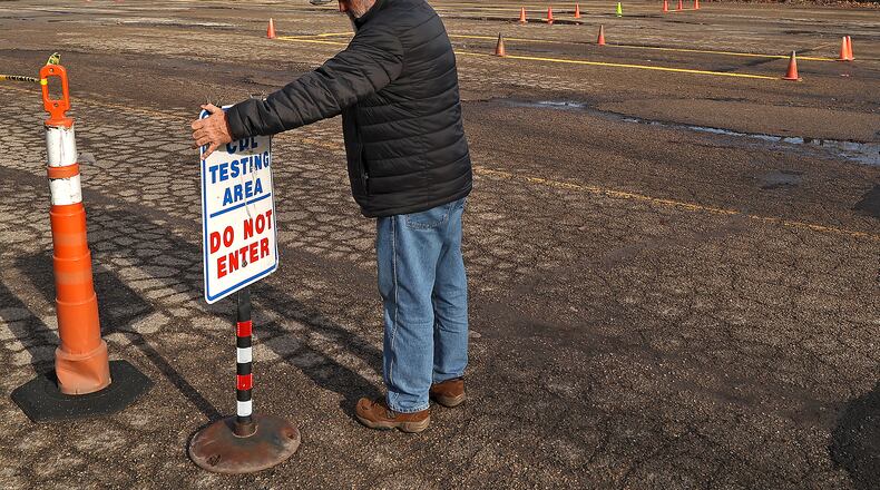 William Weekley, a Clark State instructor and CDL examiner, straightens a sign at the new testing facility on Tremont City Road. BILL LACKEY/STAFF