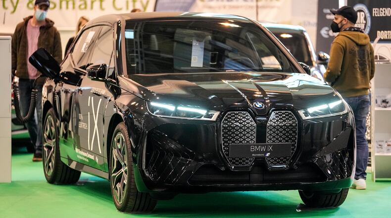 Visitors watch the new full electric car BMW iX iat the Motor Show in Essen, Germany, Thursday, Dec. 2, 2021. (AP Photo/Martin Meissner)
