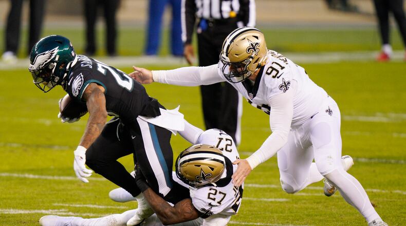 Philadelphia Eagles' Miles Sanders (26) is tackled by New Orleans Saints' Malcolm Jenkins (27) and Trey Hendrickson (91) during the first half of an NFL football game, Sunday, Dec. 13, 2020, in Philadelphia. (AP Photo/Chris Szagola)