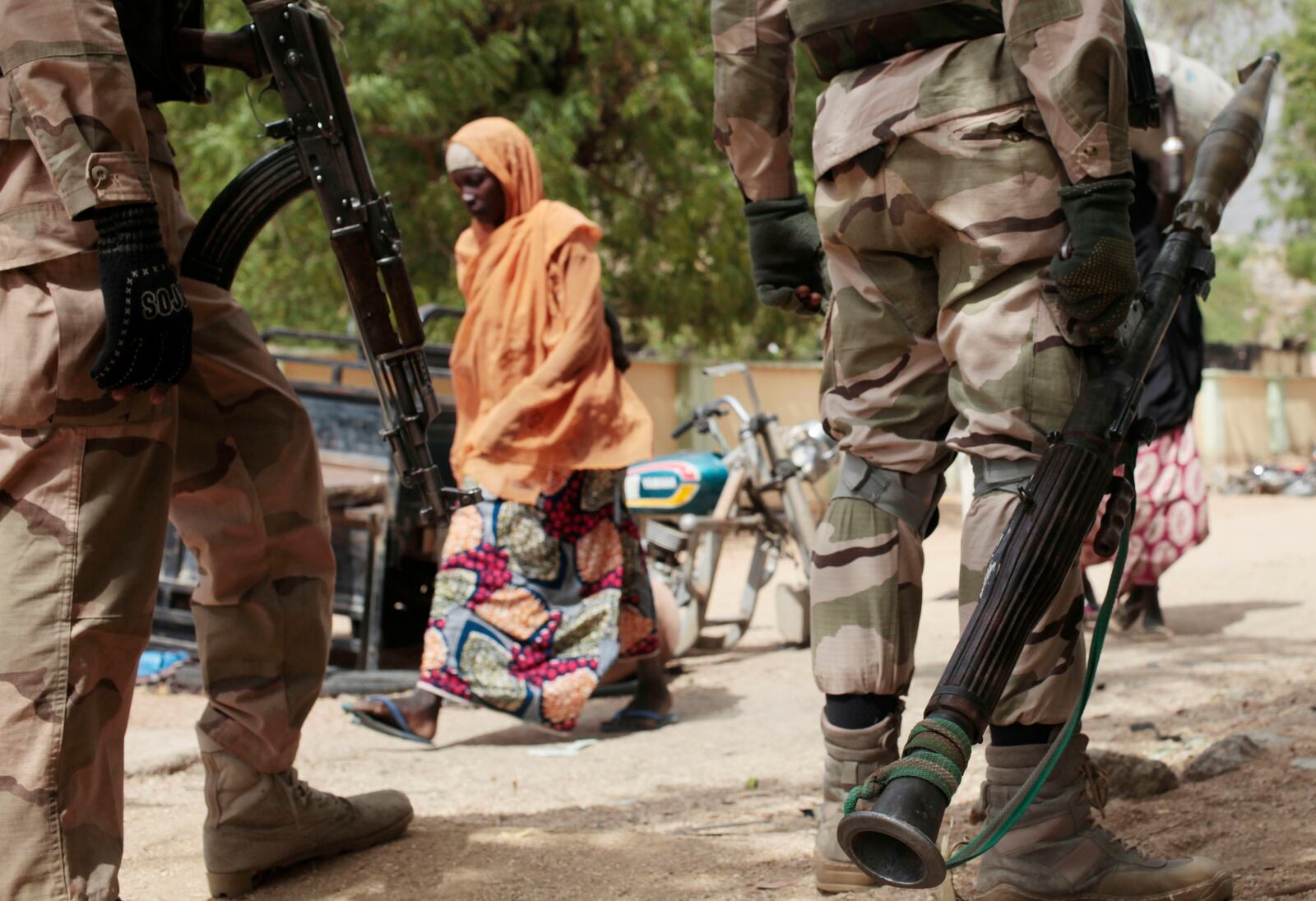 FILE - A woman walks past Nigerian soldiers at a checkpoint in Gwoza, northeast, Nigeria, April 8, 2015. (AP Photo/Lekan Oyekanmi, File)