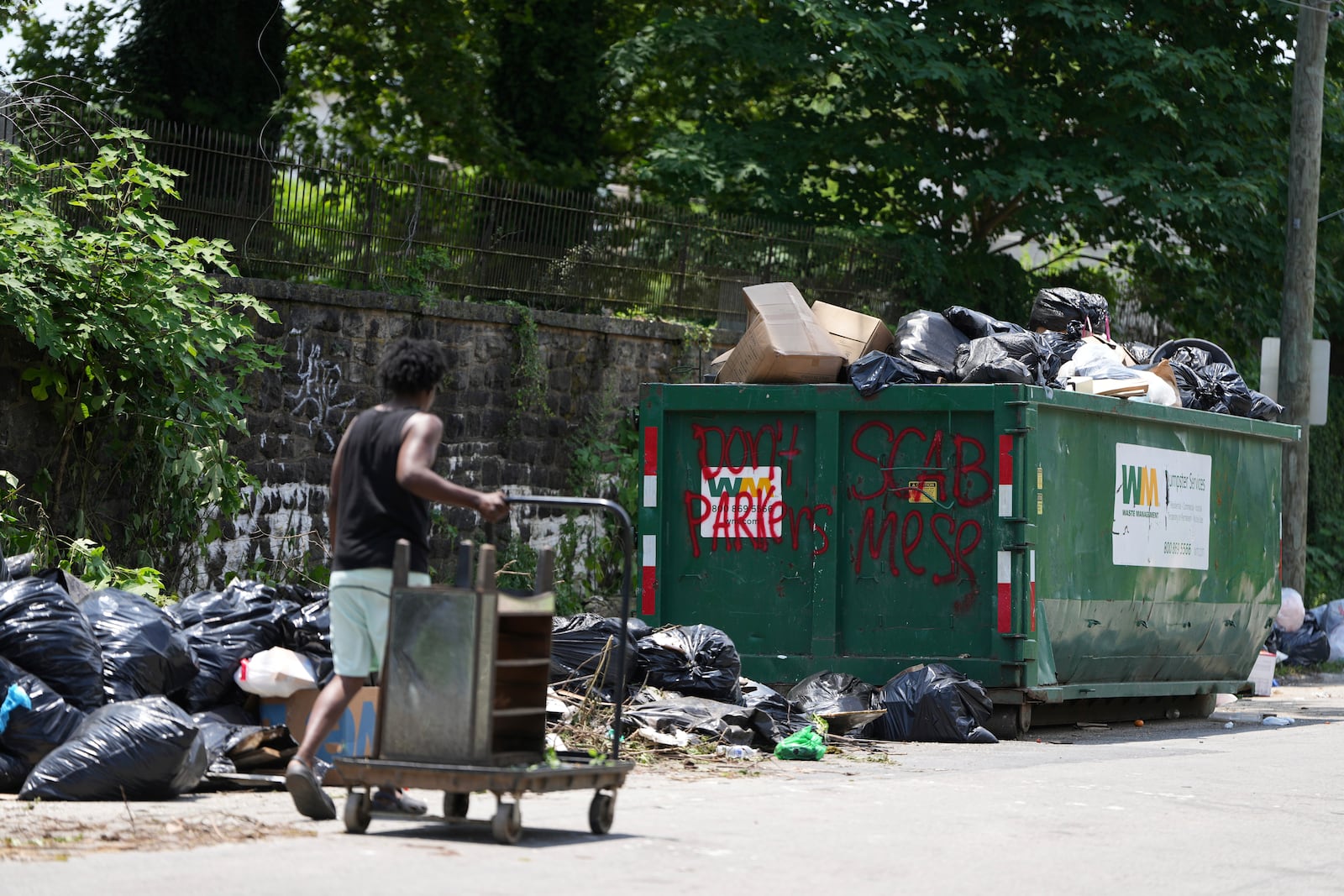 A man takes trash to a garbage collection site, Wednesday, July 9, 2025, in Philadelphia. (AP Photo/Matt Slocum)