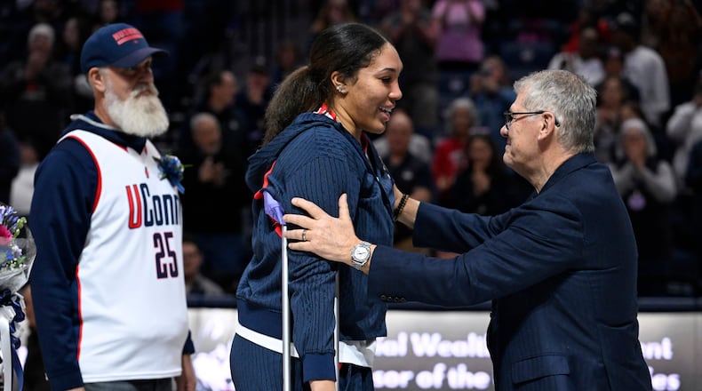 UConn head coach Geno Auriemma, right, reaches for UConn forward Ice Brady, center, as she is honored in a Senior Day ceremony after an NCAA college basketball game against Providence, Sunday, Feb. 22, 2026, in Storrs, Conn. (AP Photo/Jessica Hill)