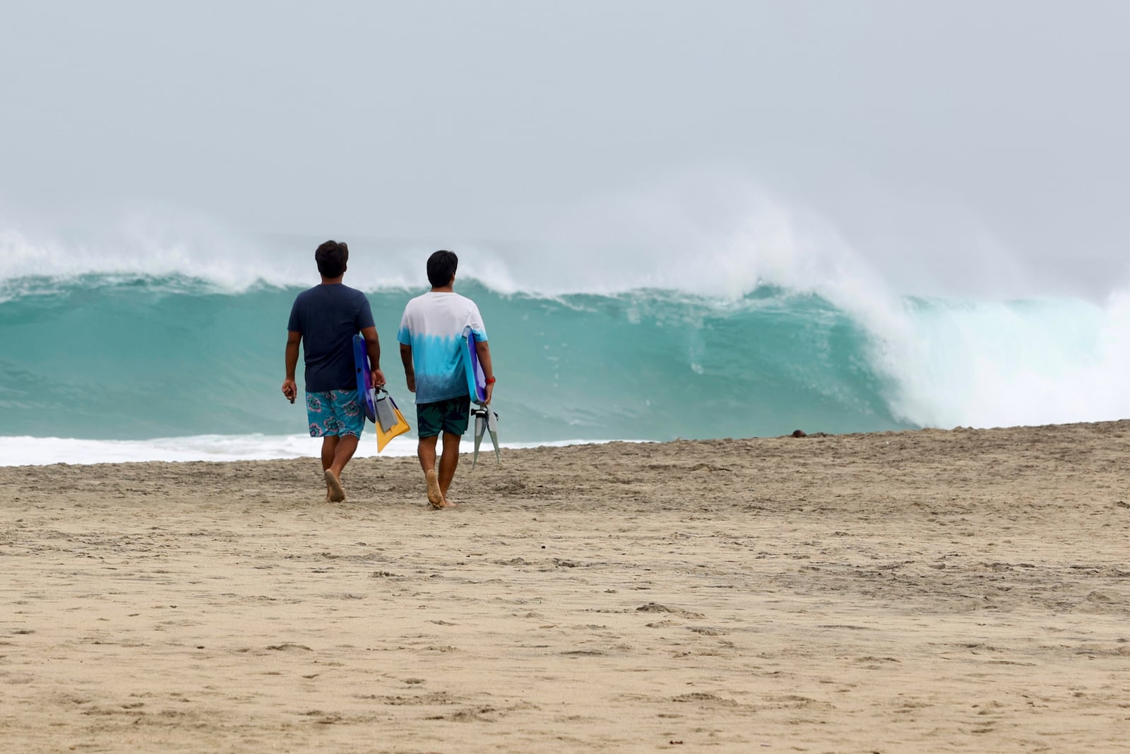 People walk on Zicatela beach prior to the arrival of Hurricane Erick in Puerto Escondido, Oaxaca state, Mexico, Wednesday, June 18, 2025. (AP Photo/Luis Alberto Cruz)