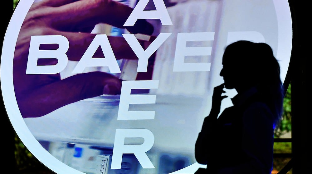 FILE - A woman walks in front of a logo of Bayer AG at the Financial News Conference in Leverkusen, Germany, Feb. 27, 2020. (AP Photo/Martin Meissner, File)