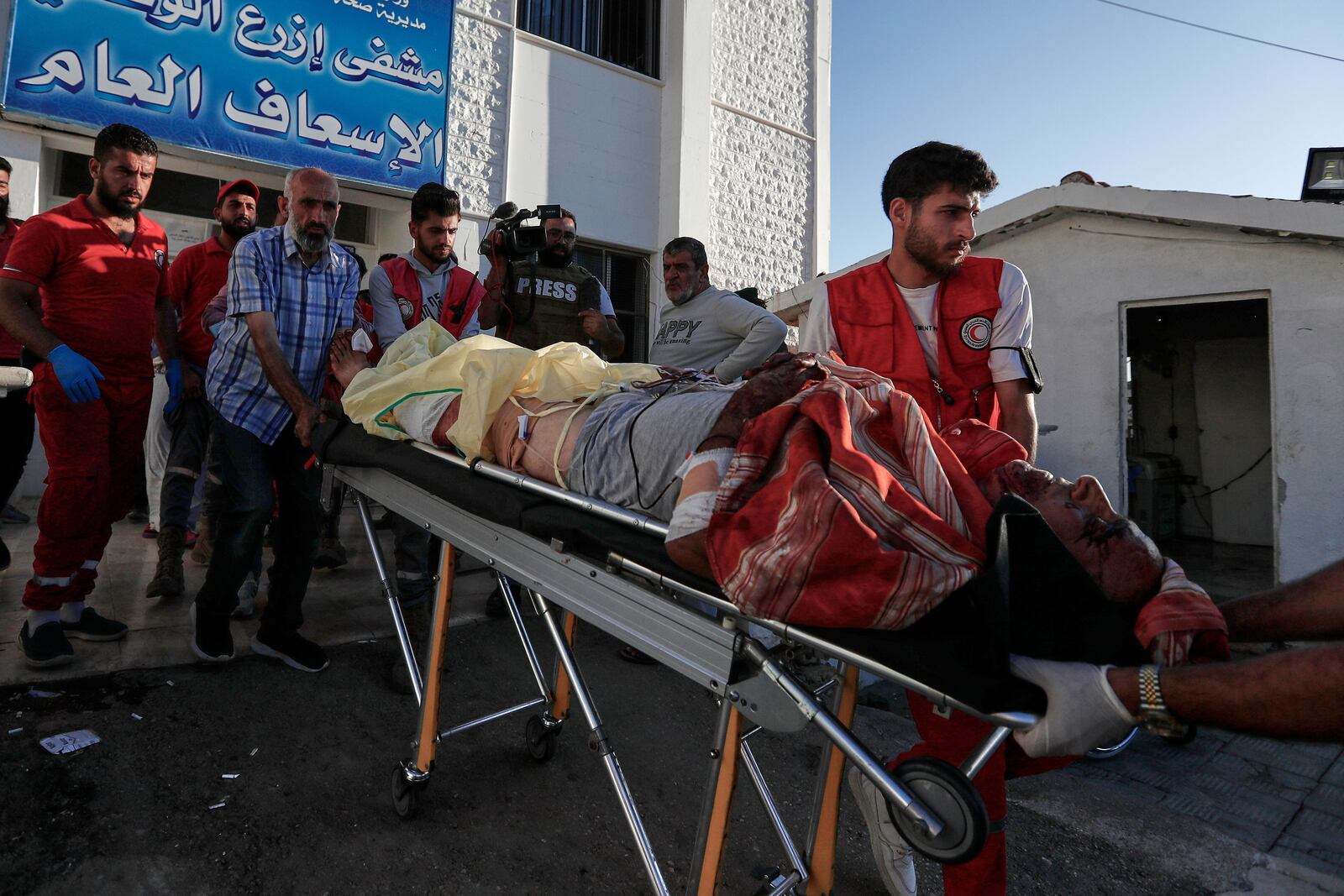 Syrian Red Crescent volunteers carry a man who was injured during clashes between Sunni Bedouin clans and Druze militias, at Ezraa hospital, southern Syria, Monday, July 14, 2025. (AP Photo/Omar Sanadiki)
