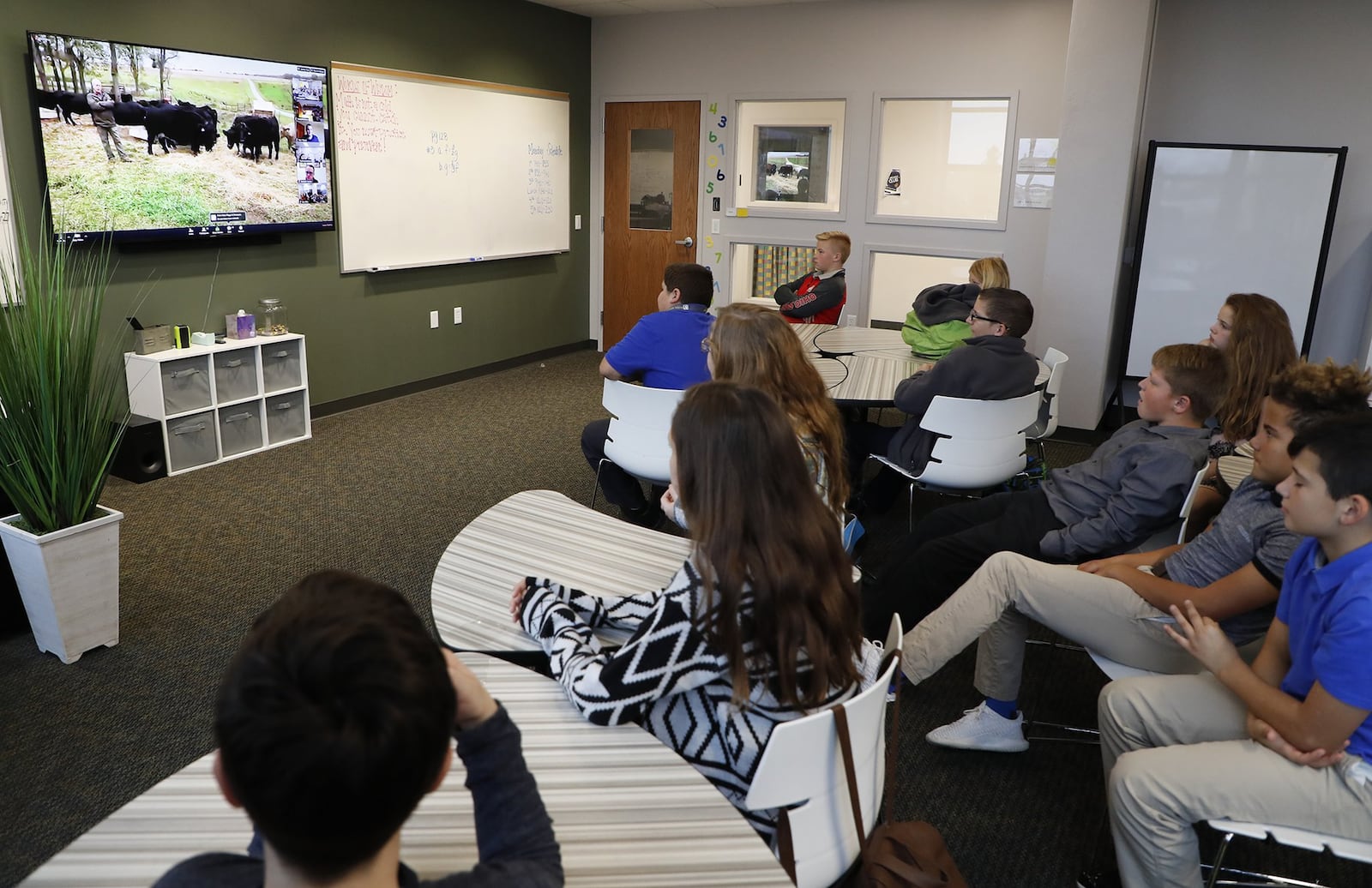 Global Impact STEM Academy students go on a virtual field trip as they listen and ask questions of a farmer in his field with his cows from their classroom. Bill Lackey/Staff