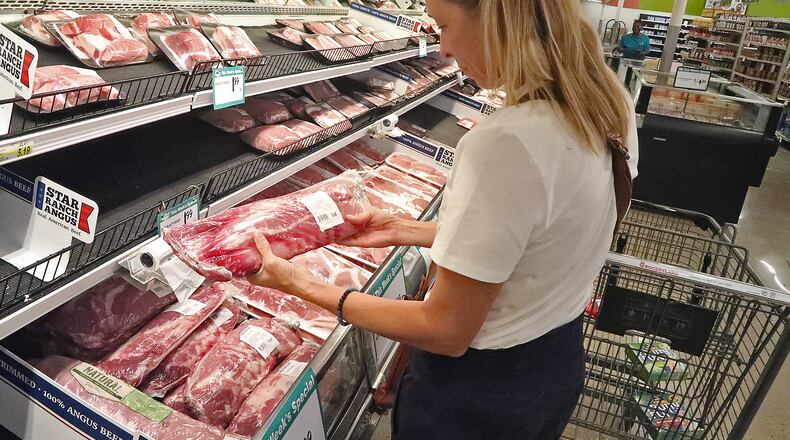 Lori Driskill-Lange looks over the meat at Groceryland on South Limestone Street Thursday. Lori said her family has decided to buy half a cow directly from a farm to help combat the rising price of meat. BILL LACKEY/STAFF