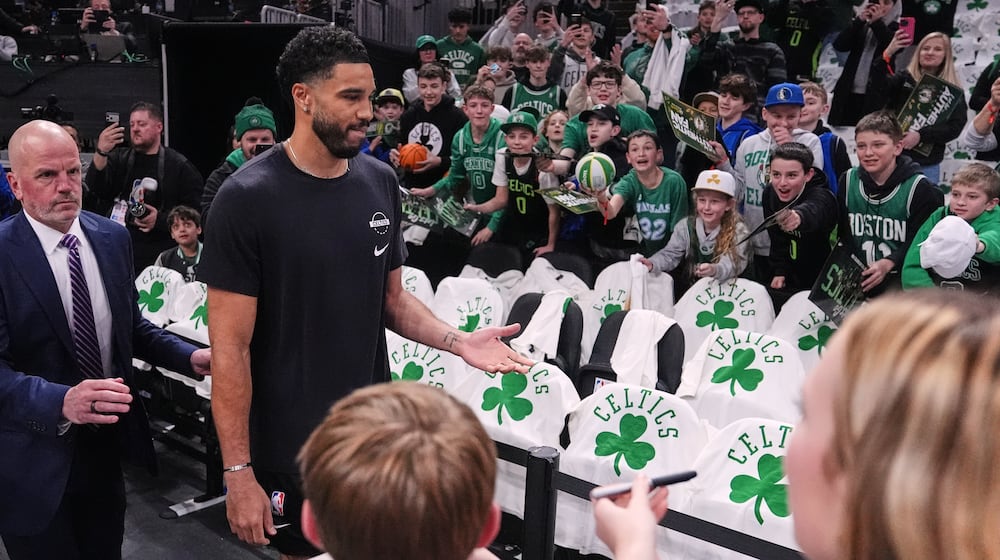 Boston Celtics forward Jayson Tatum, second from left, who has not played since injuring his achilles tendon during the 2025 NBA playoffs, is greeted by fans during a practice prior to an NBA basketball game against the Dallas Mavericks, Friday, March 6, 2026, in Boston. (AP Photo/Charles Krupa)