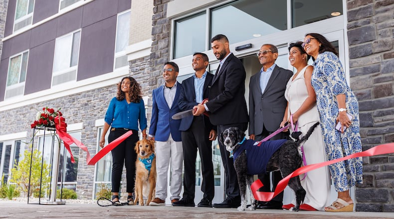 Joshua and Roshan Patel (center) cut a ribbon surrounded by family members to celebrate the opening of a dual-branded Mariott near the Mall at Fairfield Commons, Sept. 5, 2025. The family owns and operates Scarlet and Gray Hospitality. BRYANT BILLING / STAFF