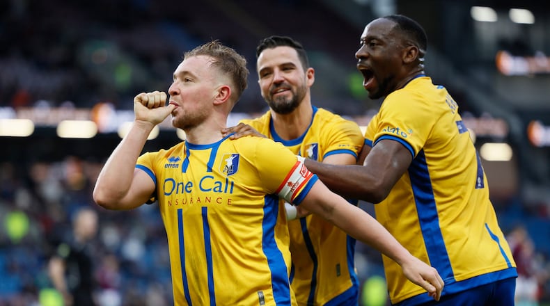 Mansfield Town's Louis Reed, left, celebrates scoring during the English FA Cup fourth round soccer match between Burnley and Mansfield Town in Burnley, England, Saturday Feb. 14, 2026. (Richard Sellers/PA via AP)