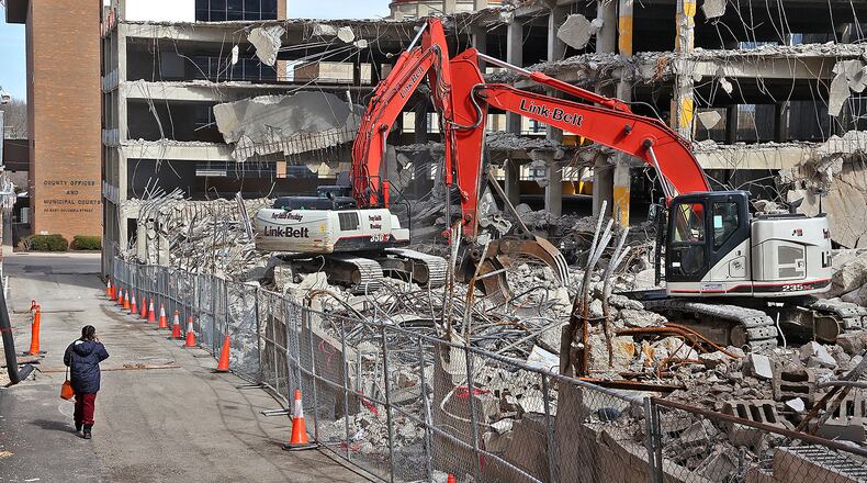 A woman walks down an alley as a crew from Tony Smith Wrecking tears down the Bushnell Parking Garage. BILL LACKEY/STAFF