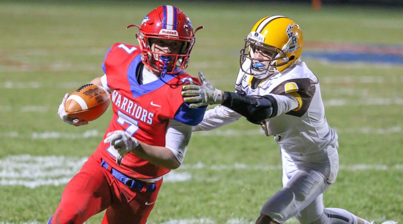 Northwestern High School’s Eli Berner runs past Kenton Ridge’s Drew Miller during their game at Taylor Field on Friday, Oct. 19. The Warriors won 21-14. MICHAEL COOPER/CONTRIBUTED