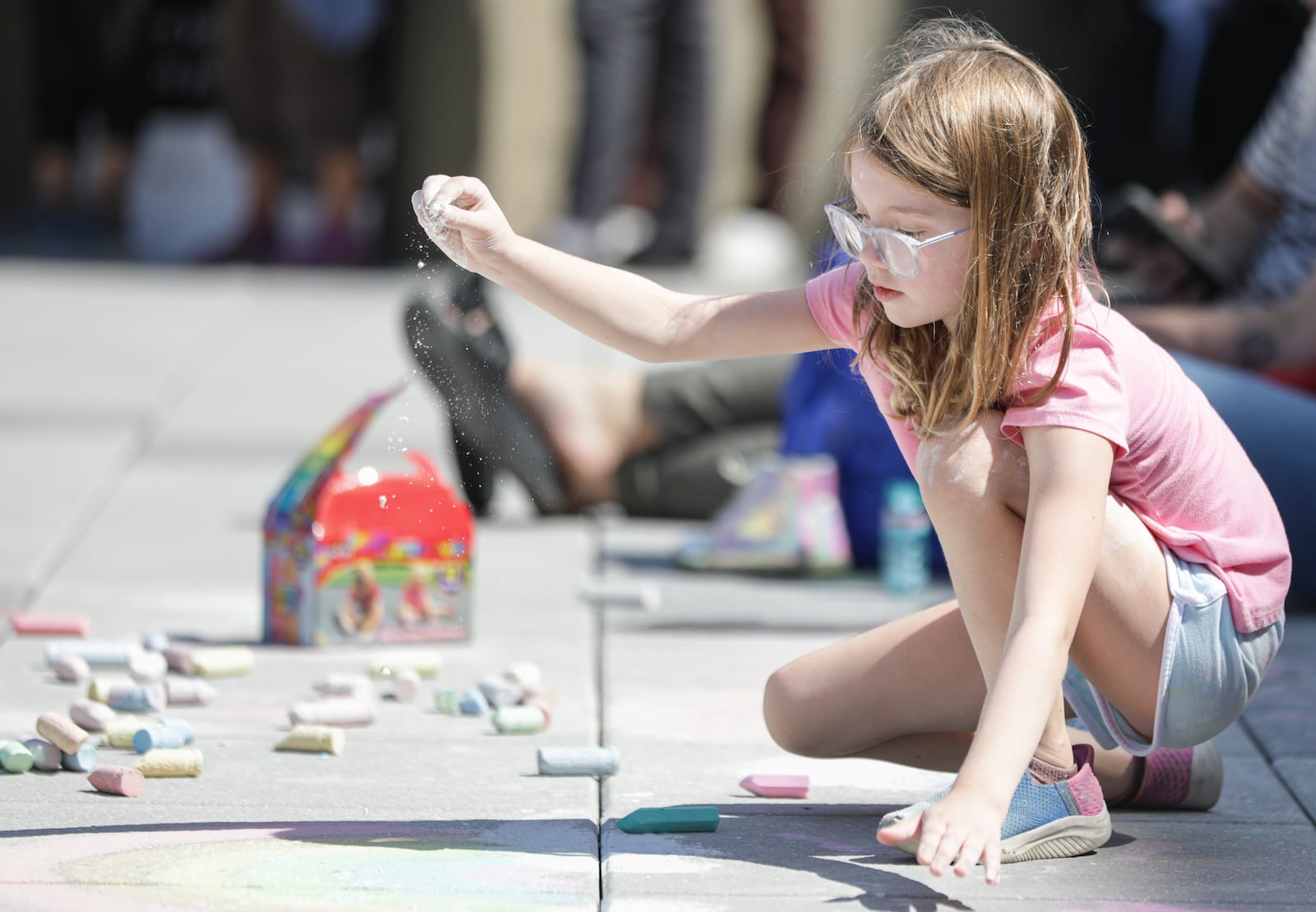 Vivian Shorts spreads chalk dust over a drawing during "Love Thy Neighbor," on Saturday, Aug. 2, at City Hall Plaza in downtown Springfield. The event was organized by Springfield G92, a coalition of churches that says it is "committed to the safety and dignity of our Haitian neighbors and friends." Over a dozen people spoke, and two choirs performed. The organization said the goal of the event was to "project love, unity and suport for our immigrant neighbors and community." BRYANT BILLING / STAFF