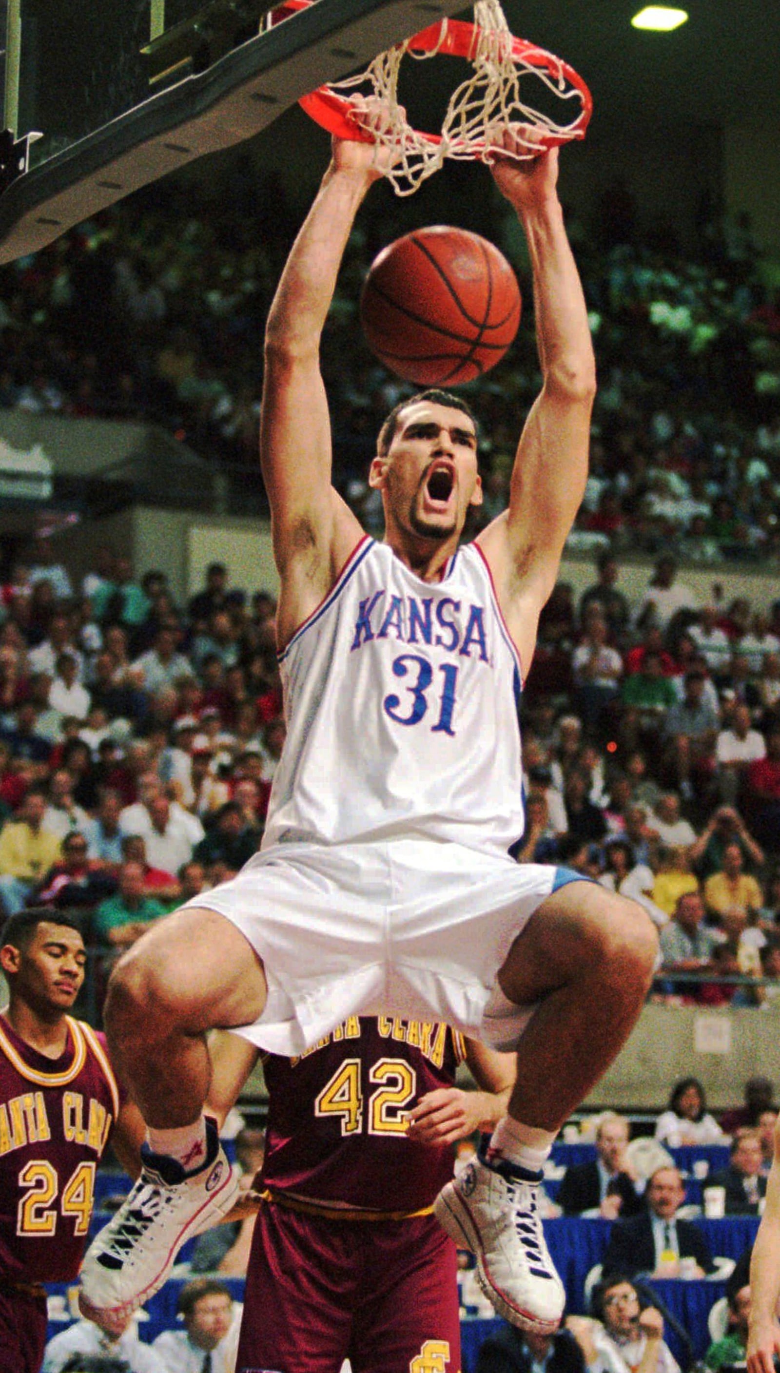FILE - Kansas center Scot Pollard slam dunks against Santa Clara during the first half of their second round NCAA West Regional game Sunday, March 17, 1996, in Tempe, Ariz. Behind Pollard are Santa Clara's Brendan Graves (42) and Marlon garnett (24). (AP Photo/Jeff Robbins, File)