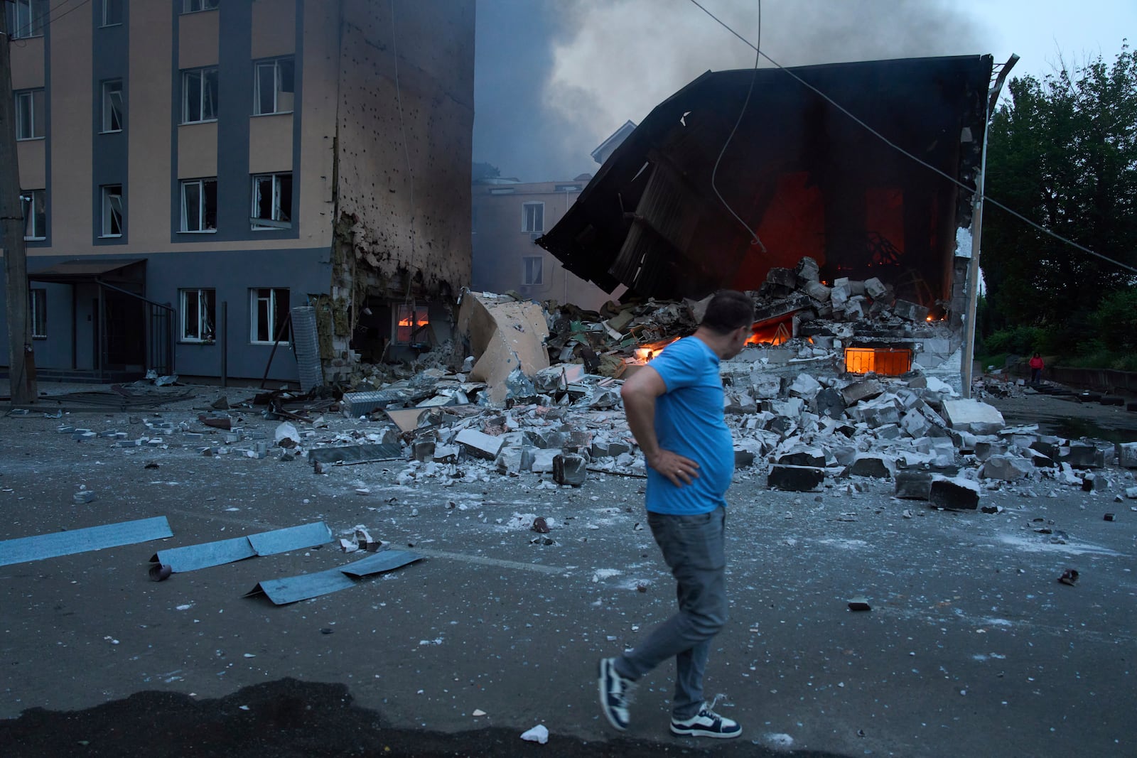A resident reacts as he passes by burning debris following Russia's massive missile and drone attack in Kyiv, Ukraine, Tuesday, June 10, 2025. (AP Photo/Efrem Lukatsky)