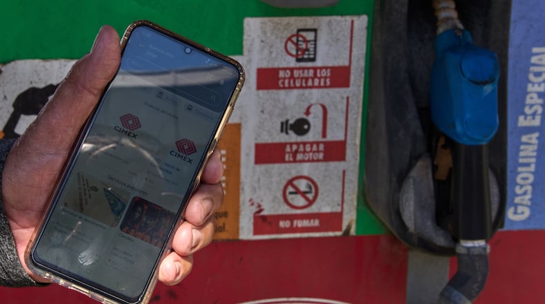 Retiree Jorge Reyes shows his phone with the app "El Ticket" which is used to reserve a place in line to buy rationed gasoline in Havana, Cuba, Monday, Feb. 16, 2026. (AP Photo/Ramon Espinosa)