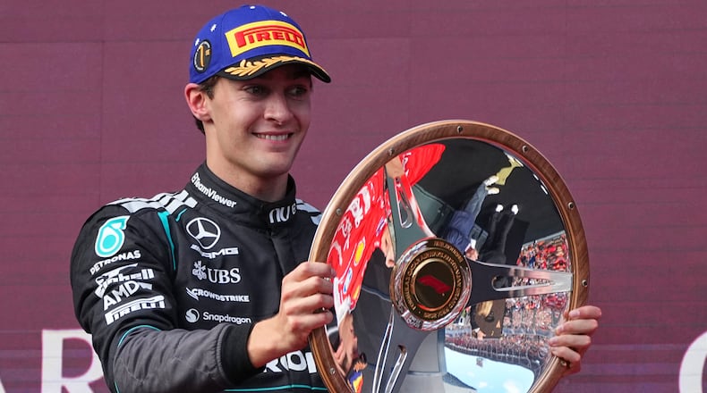 Mercedes driver George Russell of Britain celebrates on the podium with his trophy after winning the Australian Formula One Grand Prix at Albert Park, in Melbourne, Australia, Sunday, March 8, 2026. (AP Photo/Scott Barbour)