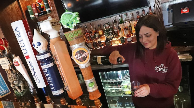 Ciera McDermott, a bartender at O’Conners Irish Pub, pours a customer a drink to-go Wednesday. BILL LACKEY/STAFF