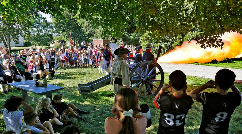 Students plug their ears as members of the First Mad River Light Artillery fire their canon Friday, Sept. 1, 2023 during the Fair at New Boston's Education Day. BILL LACKEY/STAFF
