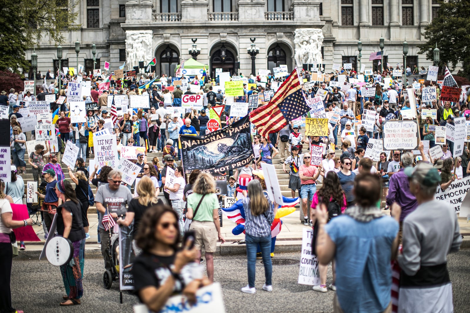 Protesters rally at the state capitol in Harrisburg, Pa., during the Day of Action protest against the Trump Administration. Saturday, April 19, 2025. (Zach Gleiter/The Patriot-News via AP)