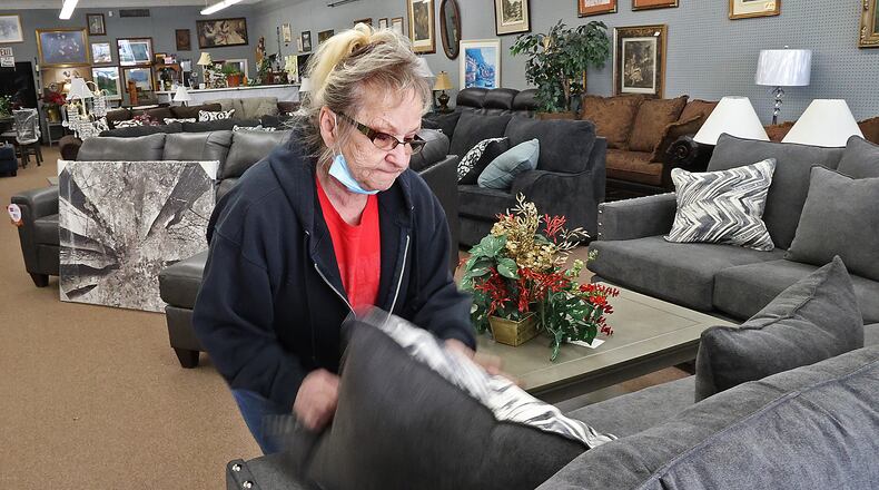 Sue Call, owner of Sue's Furniture in Springfield, fluffs the pillows on a sofa in her showroom Tuesday. BILL LACKEY/STAFF
