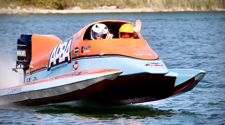 State Representative Bernie Willis, left, and F1 racing champion Chris Fairchild give a wave as they go for a ride on media day Wednesday, August 21, 2024 in a two seat high performance boat for the upcoming Wake the Lake, at Champion Park Lake. MARSHALL GORBY\STAFF