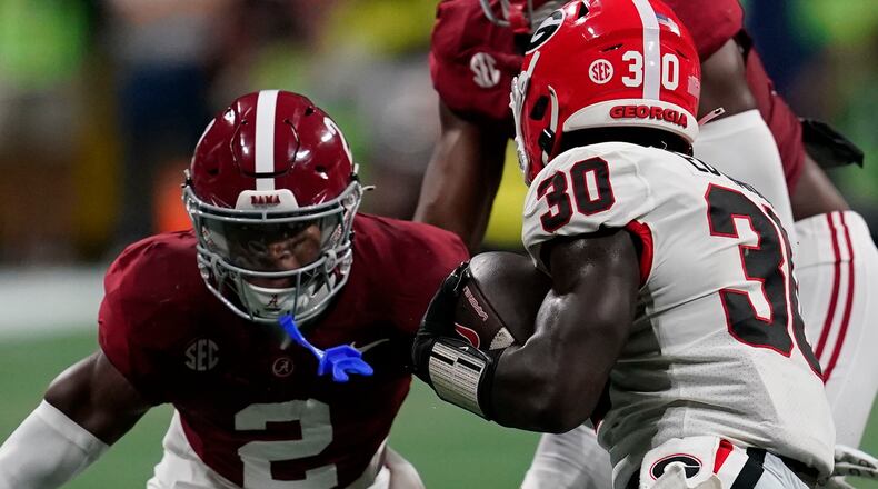 Georgia running back Daijun Edwards (30) runs the ball against Alabama defensive back Caleb Downs (2) during the first half of the Southeastern Conference championship NCAA college football game in Atlanta, Saturday, Dec. 2, 2023. (AP Photo/Mike Stewart)