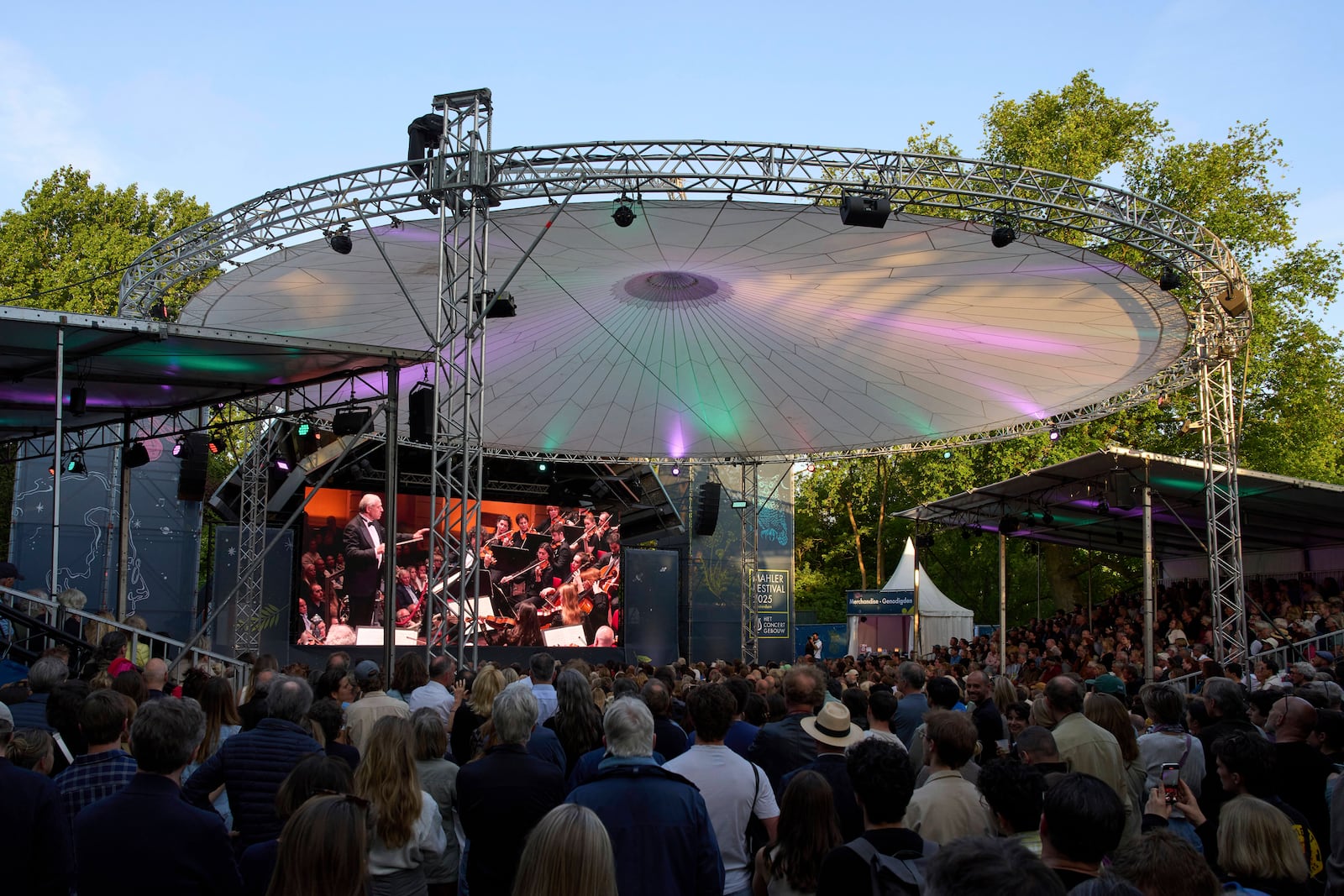 People in Vondelpark watch a video transmission of Ivan Fischer conducting the Budapest Festival Orchestra and the Netherlands Radio Choir performing Mahler's Symphony nr. 2 in the Concertgebouw in Amsterdam, Netherlands, Saturday, May 10, 2025. (AP Photo/Peter Dejong)
