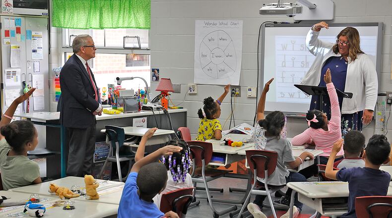 Governor Mike DeWine listens as students at Fulton Elementary School learn how to read Friday, April 14, 2023 as he tours the Springfield City school. The governor is touring schools across the state to learn about their new ready curriculum. BILL LACKEY/STAFF