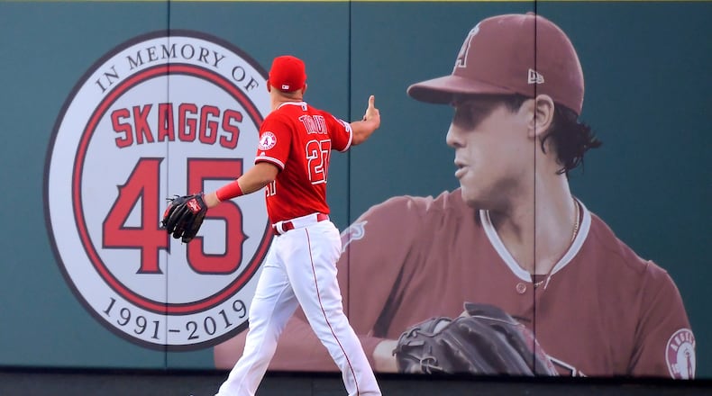 FILE - Los Angeles Angels center fielder Mike Trout gestures toward a photo of Tyler Skaggs in center field prior to a baseball game against the Detroit Tigers in Anaheim, Calif., on July 29, 2019. (AP Photo/Mark J. Terrill, File)
