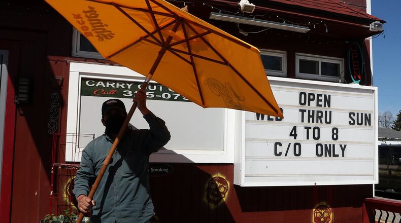 Felix Guerra, owner of Guerra’s Krazy Taco, takes down an umbrella outside the restaurant Monday. Guerra’s Krazy Taco is reopening on Wednesday after temporarily closing due to the coronavirus pandemic. BILL LACKEY/STAFF