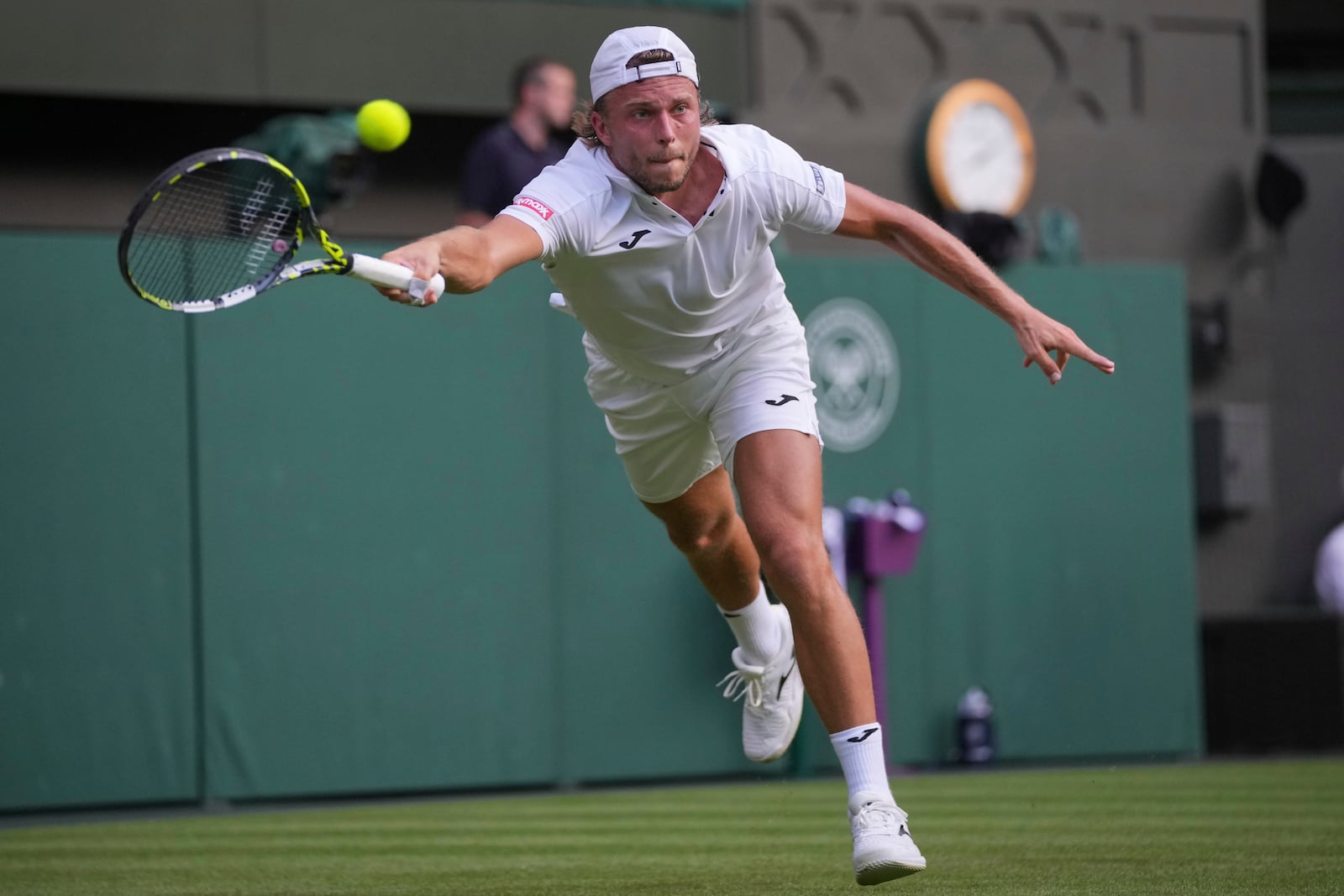 Alexandre Muller of France stretches to return to Novak Djokovic of Serbia during their first round men's singles match at the Wimbledon Tennis Championships in London, Tuesday, July 1, 2025. (AP Photo/Kin Cheung)