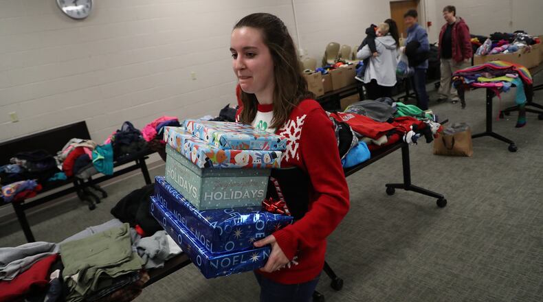 Volunteer Madison Tyler carries Christmas presents to the car for a Giving Tree recipiant Monday night at the Champaign Co Family and Children First Council’s second annual Giving Tree event for needy family’s. BILL LACKEY/STAFF